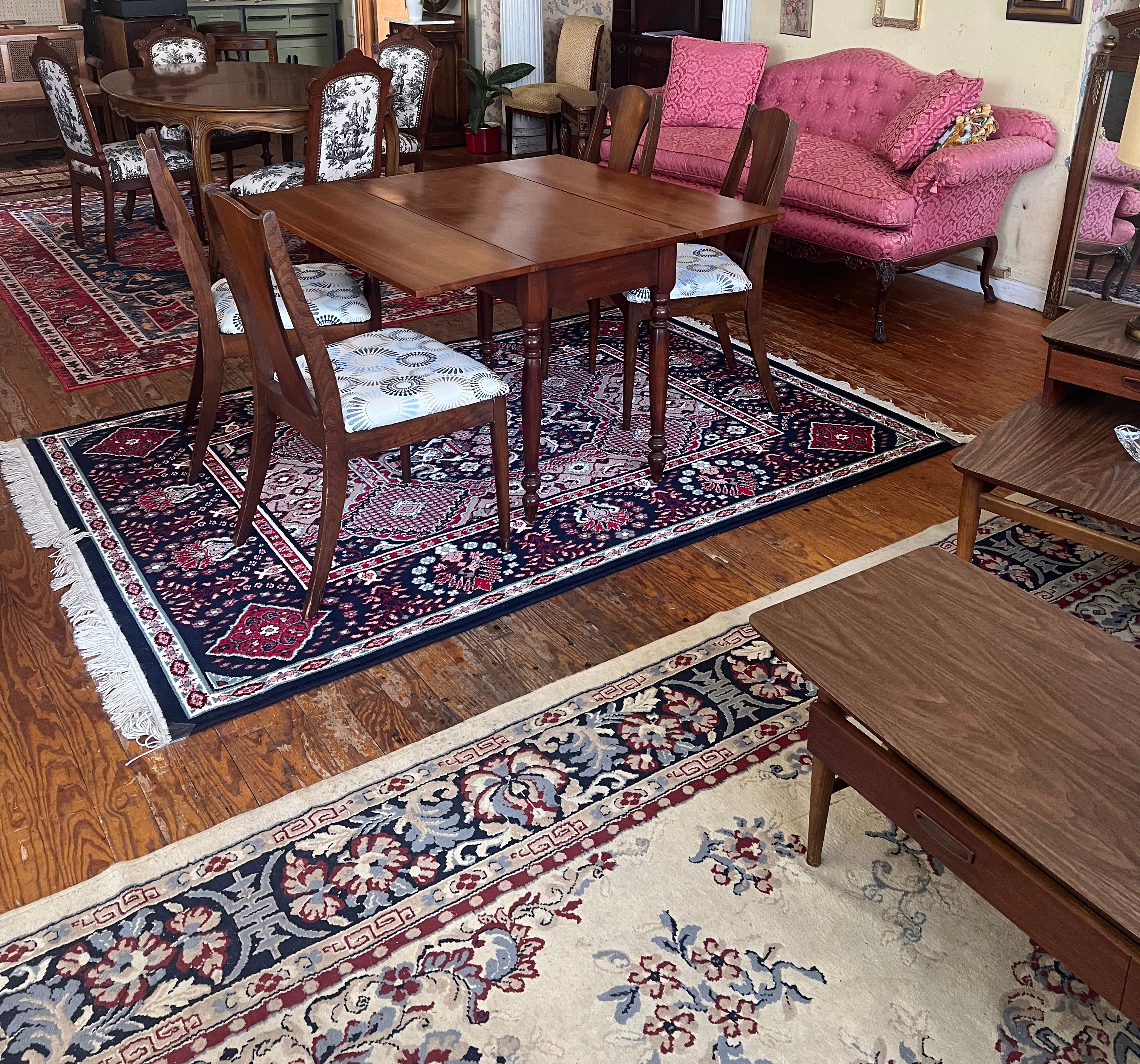 A walnut table and chairs on layered hand-knotted rugs over a wood floor